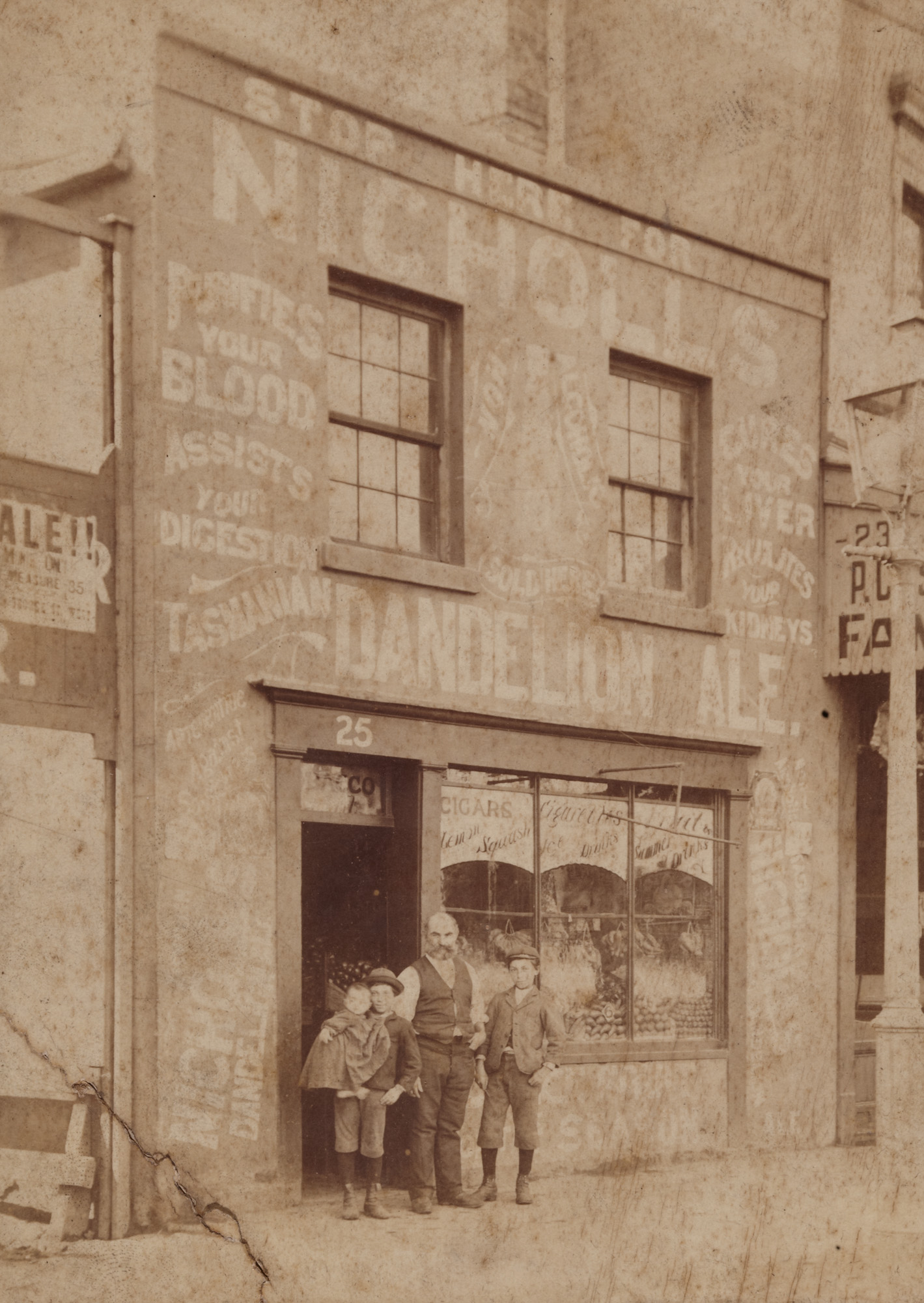 Man with two young boys, one holding an infant, outside a shop, probably in George Street West, Sydney, ca.1898 / Wall Bros. Photographers